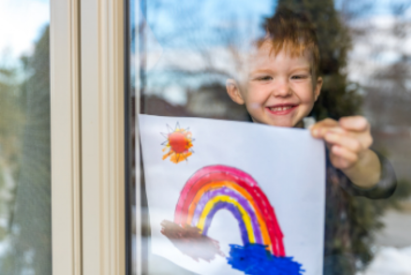 Child holding a drawing of a rainbow