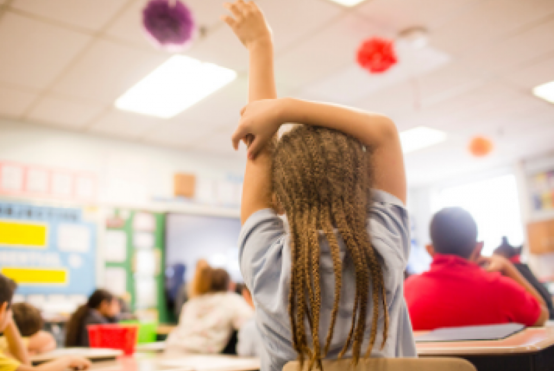 Child raising their hand in a classroom 